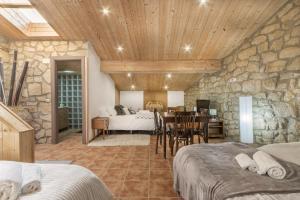 1 dormitorio con pared de piedra, cama y mesa en El Petit Maialenc, en Mayals