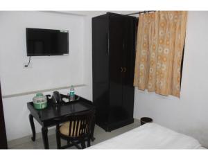 齋浦爾的住宿－"Boby Homestay", Boby Mansion, Jaipur，一间卧室配有一张桌子和一个带电视的黑色橱柜