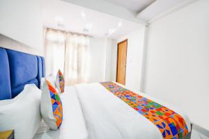 a white bedroom with a bed with a colorful blanket at FabHotel Beer Castle in Shimla