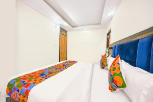 ein weißes Zimmer mit einem Bett mit bunten Kissen in der Unterkunft FabHotel Beer Castle in Shimla