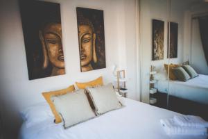 a bedroom with a white bed with paintings on the wall at AP-1 XimoApartments con VISTAS PANORÁMICAS AL MAR in Oliva