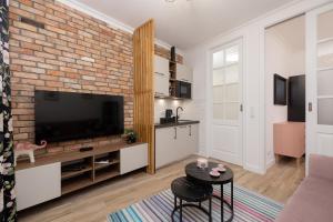 Beautiful & Stylish Apartaments Dietla with Air Conditioning by Renters في كراكوف: غرفة معيشة مع تلفزيون وجدار من الطوب