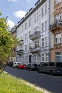 Beautiful & Stylish Apartaments Dietla with Air Conditioning by Renters في كراكوف: مبنى ابيض كبير وبه سيارات تقف على جانب شارع