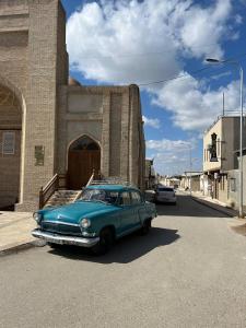 une vieille voiture bleue garée devant un bâtiment dans l'établissement Ikat Terrace, à Boukhara