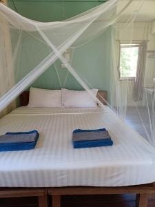 - un lit blanc avec 2 serviettes bleues dans l'établissement Mangrove House Kohyao noi, à Ban Bang Chak