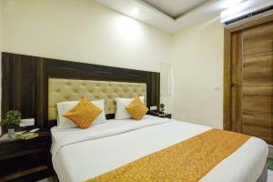 ein Schlafzimmer mit einem großen weißen Bett mit orangefarbenen Kissen in der Unterkunft Hotel IBY in Neu-Delhi