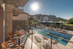 a balcony with a table and chairs and a pool at Sofibel sivota suites in Syvota
