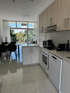 een keuken met witte kasten en een eettafel bij Seaside Bliss 1-Bed Apt in Paphos City
