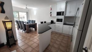 a kitchen with white cabinets and a table with chairs at Beach Court Holiday Villas 4n each guest get free Day trip Kens Klassic Kombi in Airlie Beach