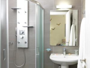 a bathroom with a sink and a shower with a mirror at Blue and White Aura Santorini traditional house in Megalochori