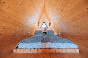 a woman sitting in a bed in a wooden room at A Frame Cabin - Valea Vinului in Vişeu de Mijloc
