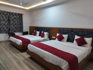 a hotel room with two beds with red pillows at Hotel Brij Palace & Restaurant in Udaipur
