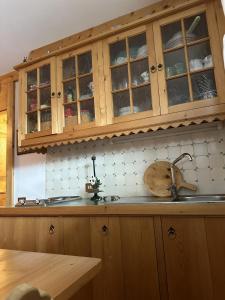 a kitchen with wooden cabinets and a sink at Pecol Cozy Apartment R&R in Cortina dʼAmpezzo