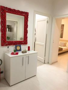 Rome Holiday Home في روما: غرفة معيشة مع مرآة حمراء وخزانة بيضاء