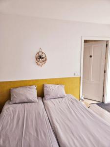 - une chambre avec deux lits et un mur avec une horloge dans l'établissement Appartement Villa Eva Rosa, à Wijk aan Zee