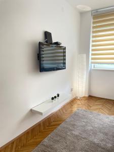 un salon avec une télévision sur un mur blanc dans l'établissement The Blue Velvet Apartment, à Belgrade