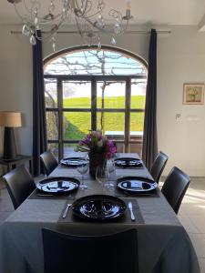 a dining room with a table with chairs and a large window at Le Hameau des Coquelicots in Damazan