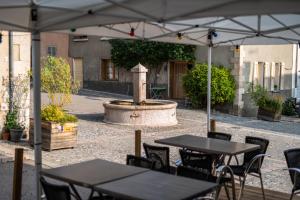 an outdoor patio with tables and chairs and a fountain at Auberge Le Glacier Bleu in Mont-Dauphin