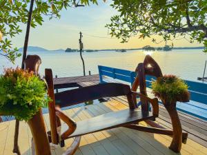 a wooden bench sitting on a dock near the water at Meena Resort in Chanthaburi