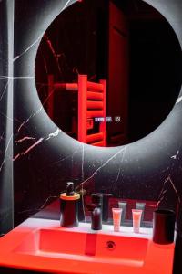 een badkamer met een rode wastafel en een spiegel bij L’alcôve de la tentation in Villeurbanne