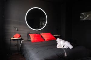 1 dormitorio con cama con almohadas rojas y espejo en L’alcôve de la tentation, en Villeurbanne