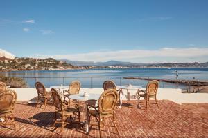 a patio with tables and chairs and a view of the water at Château de Théoule in Théoule-sur-Mer