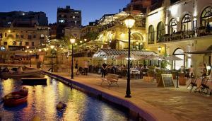 a city at night with a river and buildings at St Julians Sliema 3 minutes walk from promenade 3 bedroom apartment in Sliema