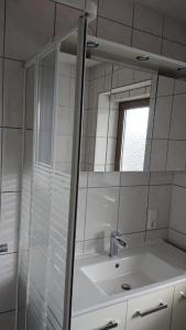 een witte badkamer met een wastafel en een spiegel bij Ferienwohnung Angelburg - Marburg Biedenkopf mit Balkon und Badewanne in Gönnern