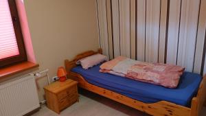 a small bedroom with a wooden bed with blue sheets at Ferienwohnung Angelburg - Marburg Biedenkopf mit Balkon und Badewanne in Gönnern