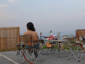 una mujer sentada en una silla en una mesa con una guitarra en Moon Camp Khaoyai, en Ban Nong Song Hong