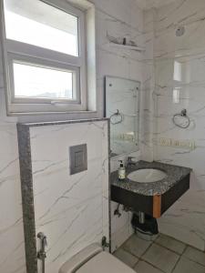 a white bathroom with a sink and a window at Medenta square 39 in Gurgaon