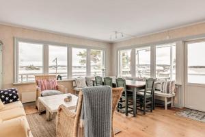 een woonkamer met een tafel, stoelen en ramen bij Seaside Bliss for Families: Home Away from Home in Stavsnäs