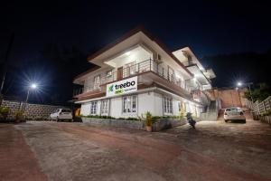 a hotel at night with cars parked in front of it at Treebo Trend Yajna Comforts in Madikeri