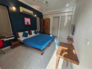 a bedroom with a bed with blue sheets and a table at Medenta square 39 in Gurgaon