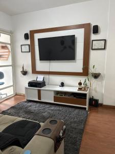 Apartamento no centro de Juiz de Fora في جويز دي فورا: غرفة معيشة مع تلفزيون بشاشة مسطحة على جدار