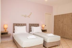 um quarto com 2 camas com lençóis brancos e 2 candeeiros em Koukos Loft Apartments em Tsilivi