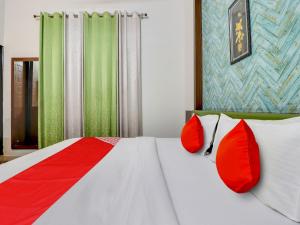 ein Schlafzimmer mit einem Bett mit roten Kissen in der Unterkunft Hotel D.Homage in Dehradun