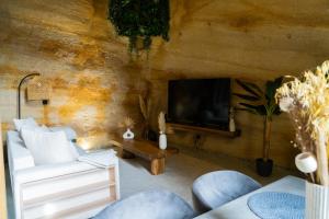 ein Wohnzimmer mit einem Sofa und einem TV in der Unterkunft Le temps suspendu, Suite troglodyte & SPA privé in Doué-la-Fontaine