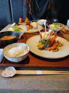 un tavolo in legno ricoperto di piatti di cibo e bacchette di Healing Inn Osaka Fukushima ad Osaka