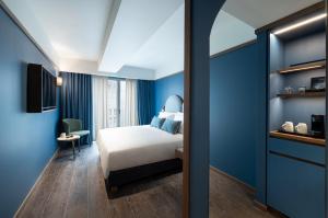 a bedroom with a bed and a blue wall at Mitsis N'U Piraeus Port in Piraeus