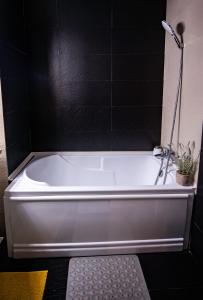 a white bath tub in a bathroom with black tiles at Coral Residence in Mamaia