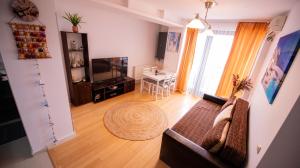 Sala de estar con sofá, TV y mesa en Coral Residence, en Mamaia