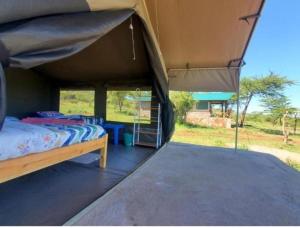 1 dormitorio con 1 cama y 1 tienda grande en kubwa mara safari lodge tent camp en Sekenani
