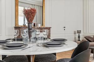une table à manger avec des verres et un vase de fleurs dans l'établissement Interior Design - Apartment 6P-1BR - Tour Eiffel, à Paris
