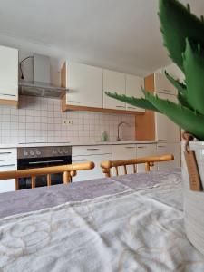 una cucina con armadi bianchi, tavolo e sedie di Haus Kampl - Appartement Ödensee a Obersdorf