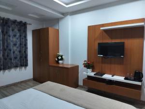 Hotel Brij Palace & Restaurant في أودايبور: غرفة فندقية بسرير وتلفزيون بشاشة مسطحة