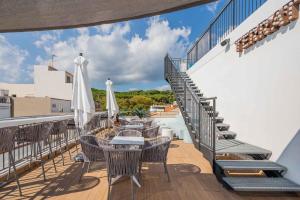 einen Balkon mit Tischen und weißen Sonnenschirmen in der Unterkunft Neptuno Apartments in Calella