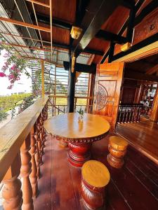 una mesa de madera y taburetes en el balcón en Biệt thự gỗ Wooden House Quy Nhơn cạnh biển, en Quy Nhon