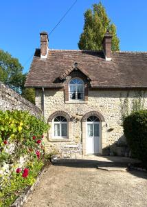 een stenen huis met een witte deur en bloemen bij Charmante Maisonette à Arçonnay (72) in Arçonnay