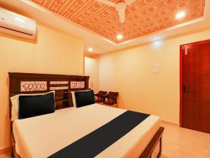 1 dormitorio con 1 cama y sillas en una habitación en Super OYO Flagship Hotel Bommarillu en Warangal